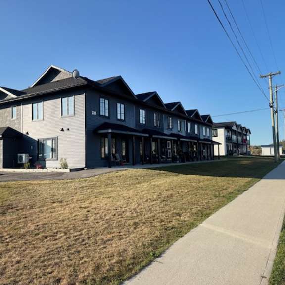 a row of houses with a sidewalk in front.
