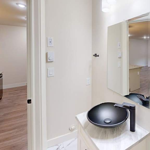 a bathroom with a black bowl sink and a mirror.