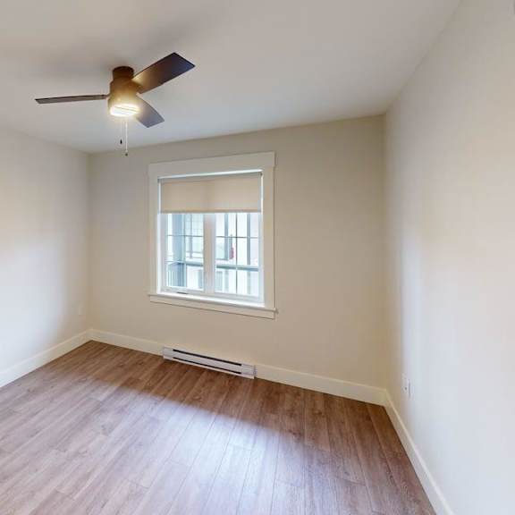 a room with a ceiling fan and a window with blinds.