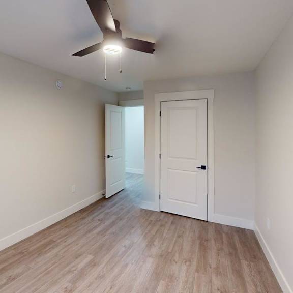 a room with a ceiling fan and wooden flooring.