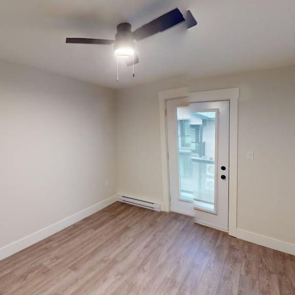 a room with a ceiling fan and a door leading to a balcony.