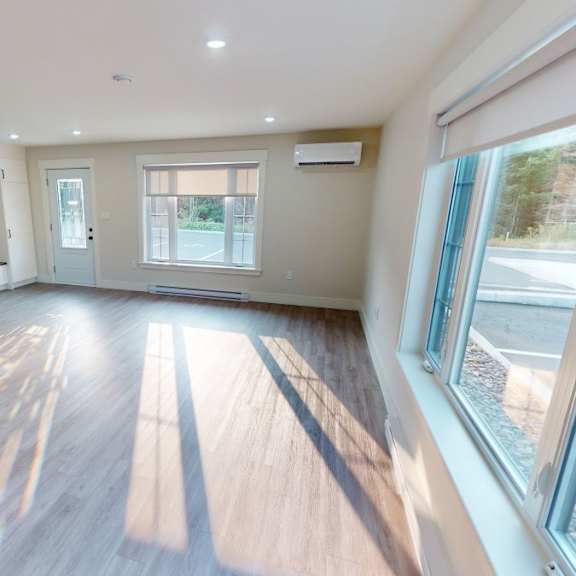a spacious room with wooden floors and a staircase on the left side.