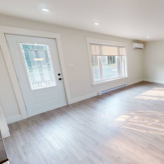 a spacious room with wooden floors and white walls.