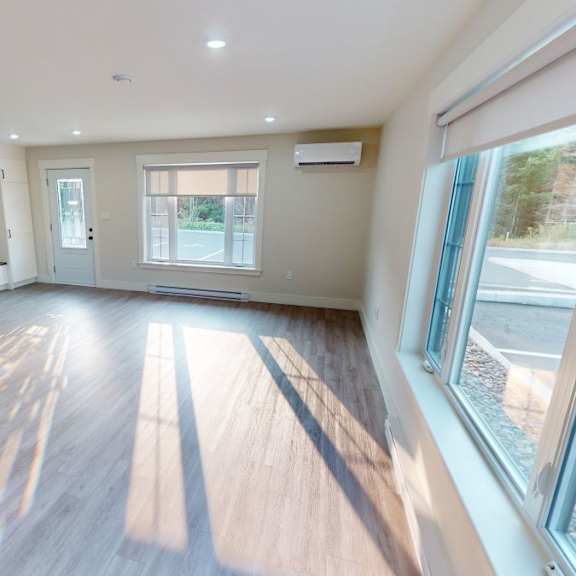 a spacious room with wooden floors and a staircase on the left side.