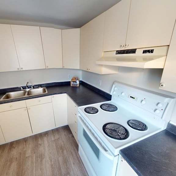 a white stove top oven with four burners is in a kitchen with white cabinets.