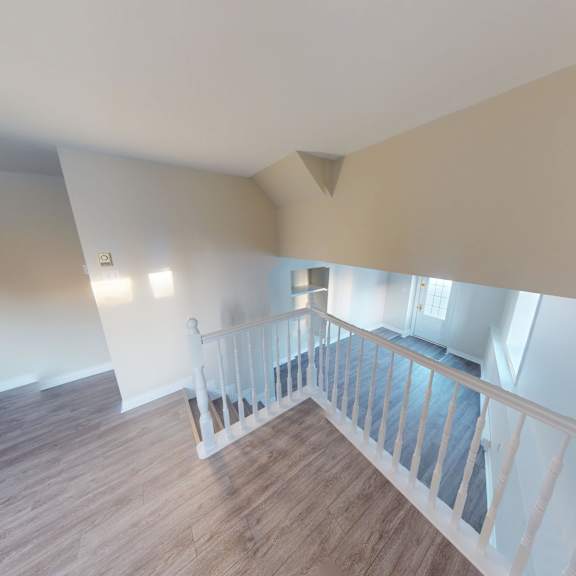 a white railing leads to a bedroom with a window.