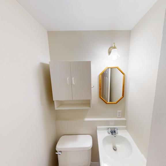 a white bathroom with a toilet, sink and mirror.