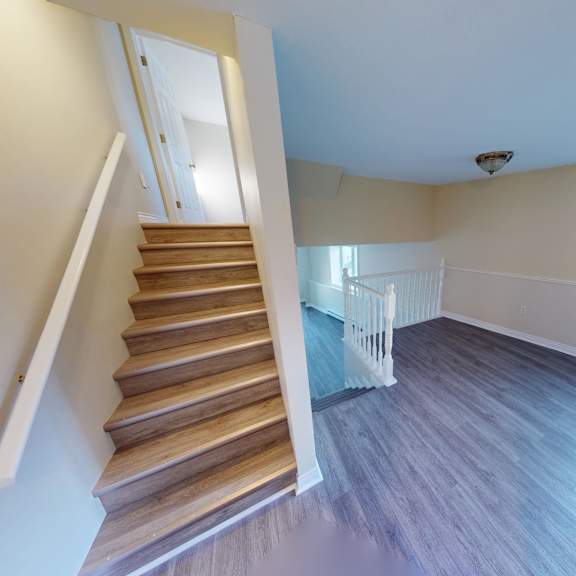a staircase with wooden steps and a white railing leads up to a bright room with a window.