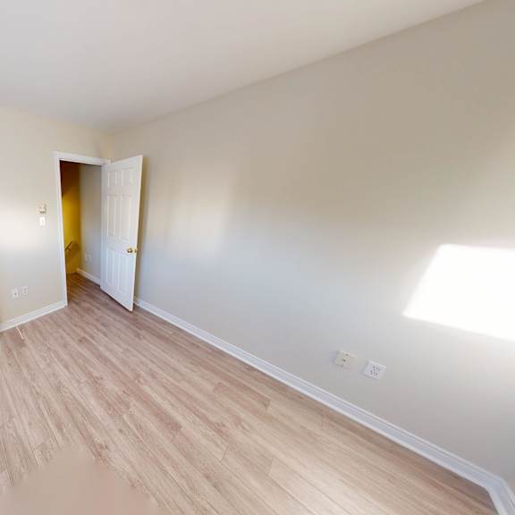 a room with a white door and a wooden floor.