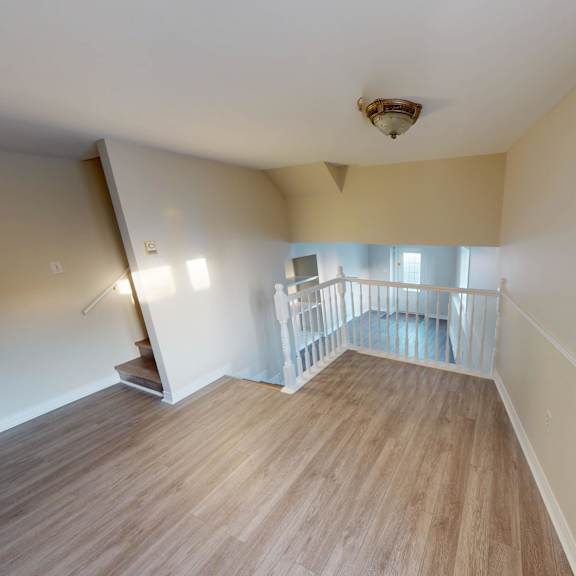 a room with wooden flooring and a staircase leading to another room.