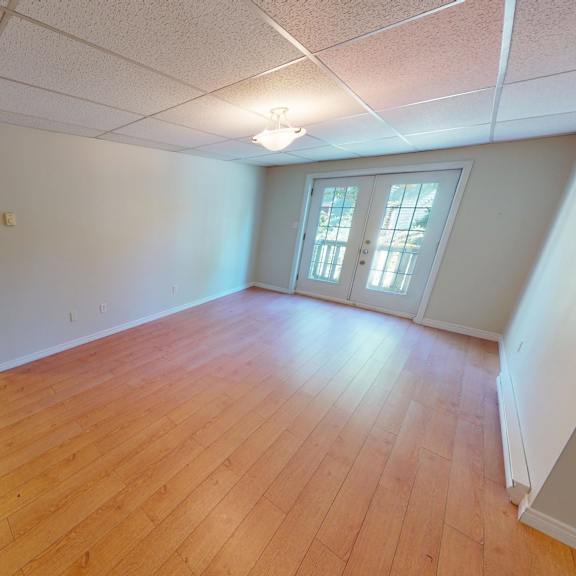 a room with wooden floors and a window with white curtains.