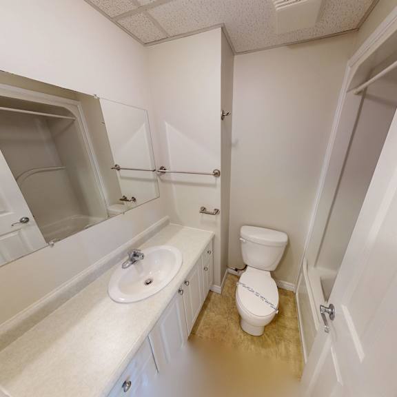 a white bathroom with a toilet, sink, and mirror.