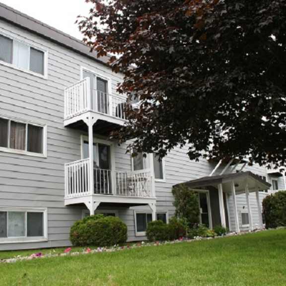 a grey apartment building with a balcony on the second floor.
