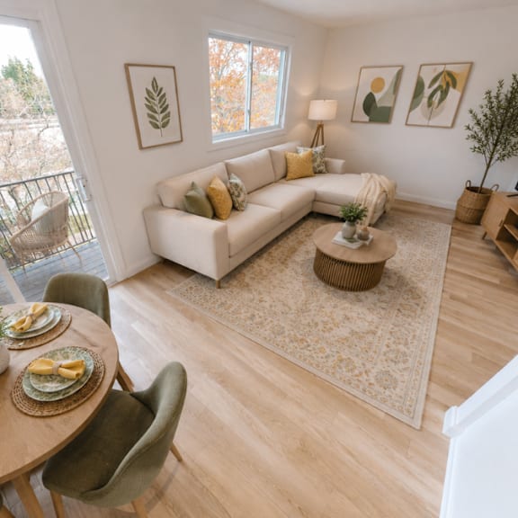 a living room with a couch, a coffee table, a television, and a dining table with chairs.