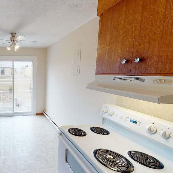 a kitchen with a stove top oven and wooden cabinets.