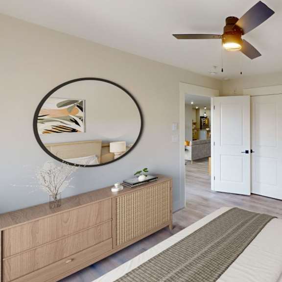 a living room with a brown rug, a white sofa, a wooden cabinet, a round mirror, and a ceiling fan.