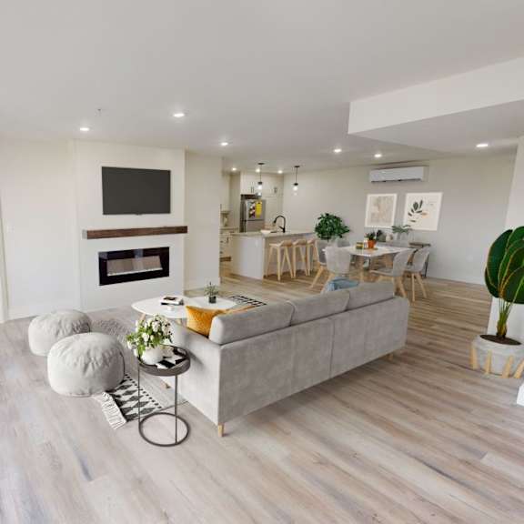 a living room with a grey couch, a television, and a plant.