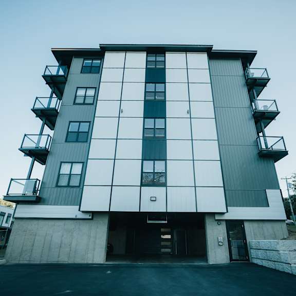 a modern building with a white and grey facade and balconies on the second floor.