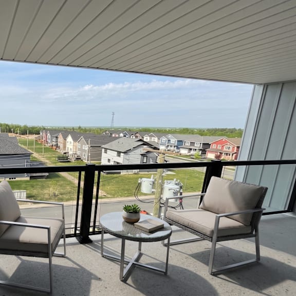 a balcony with two chairs and a table overlooking a residential area.