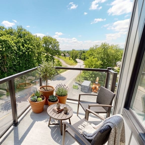 a balcony with a table and chairs overlooking a road.