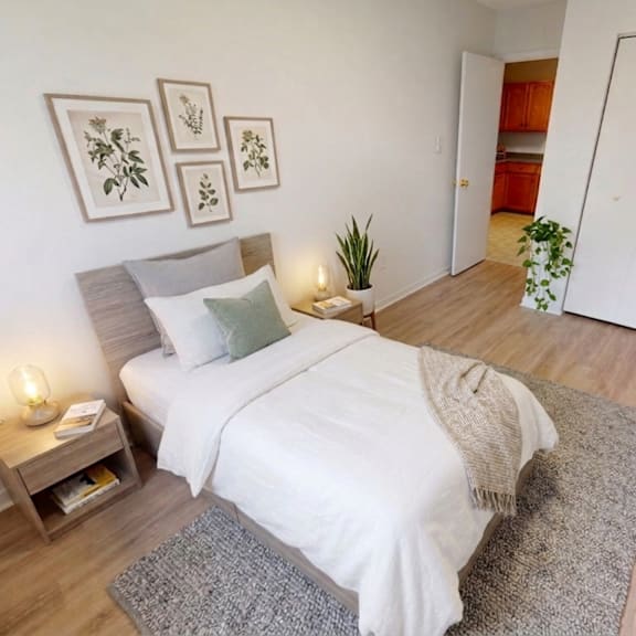 a bedroom with a bed, nightstand, and framed pictures on the wall.