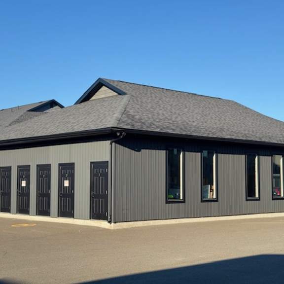 a grey building with black doors and windows.