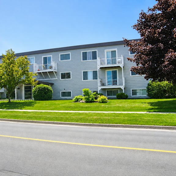a grey apartment building with a yellow line in front of it.