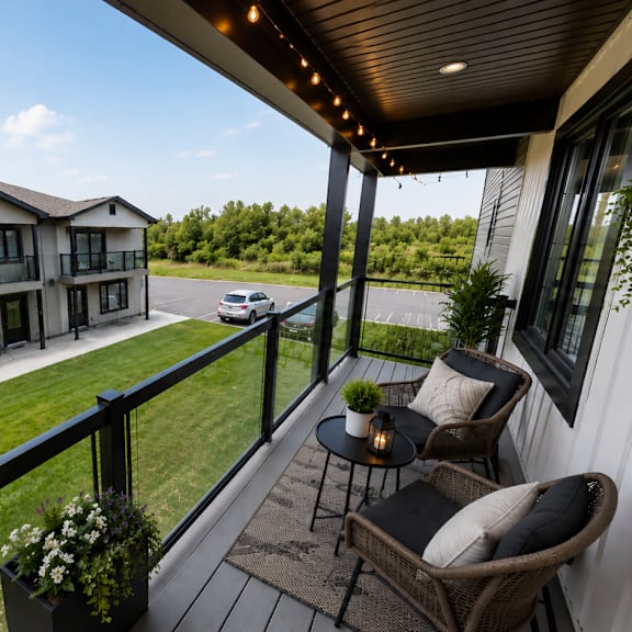 a balcony with a table and chairs overlooks a grassy area and a building.
