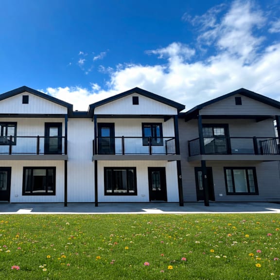 a row of modern houses with balconies and flower beds in front.
