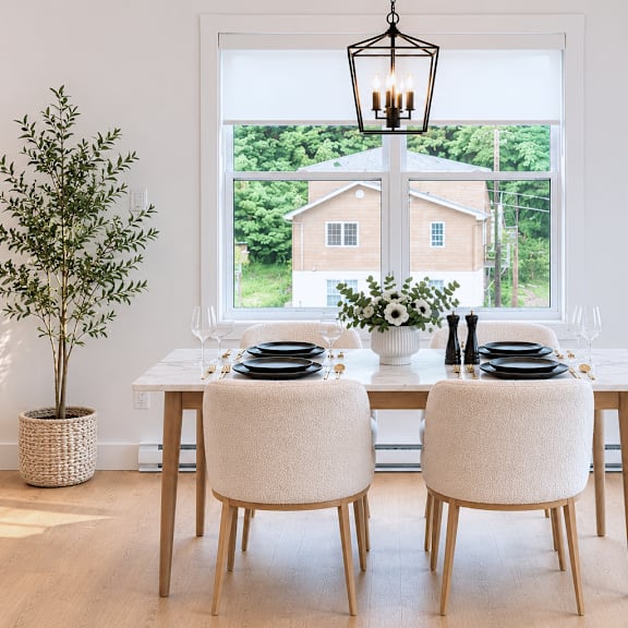 a dining room with a table set for two and a view of a house through the window.