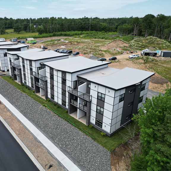 a row of modern houses are being built on a gravel lot.