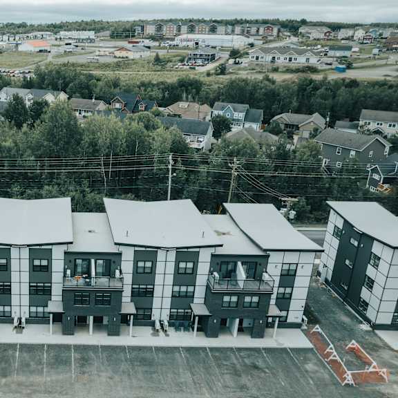 a large building complex with multiple units and a parking lot in front.