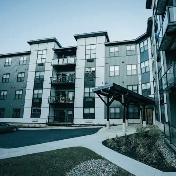 a modern apartment building with a car parked in front.