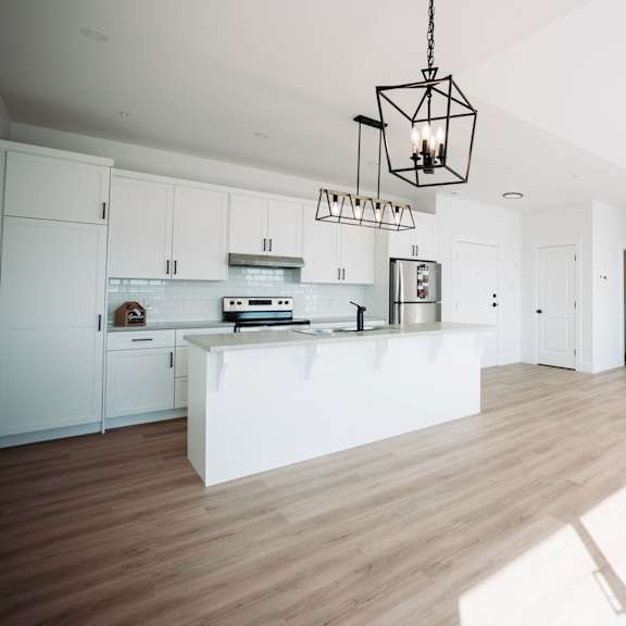 a modern kitchen with white cabinets and a wooden floor.