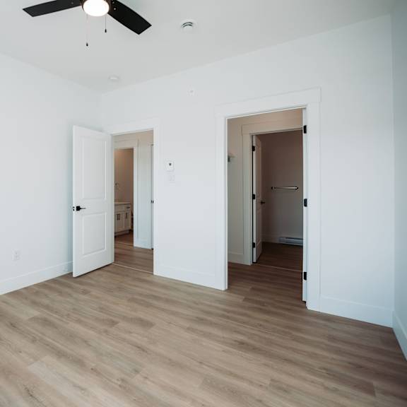 a room with a ceiling fan and wooden flooring.