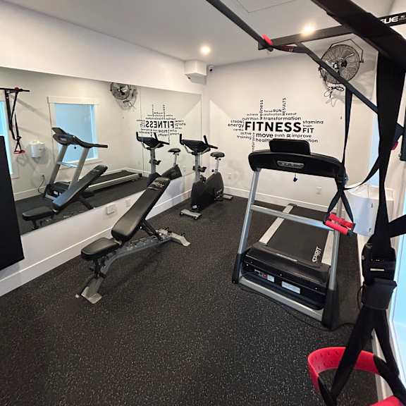 a gym with a variety of equipment including a treadmill, a stationary bike, and a rowing machine.