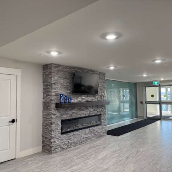 a living room with a stone fireplace and a flat screen tv mounted above it.