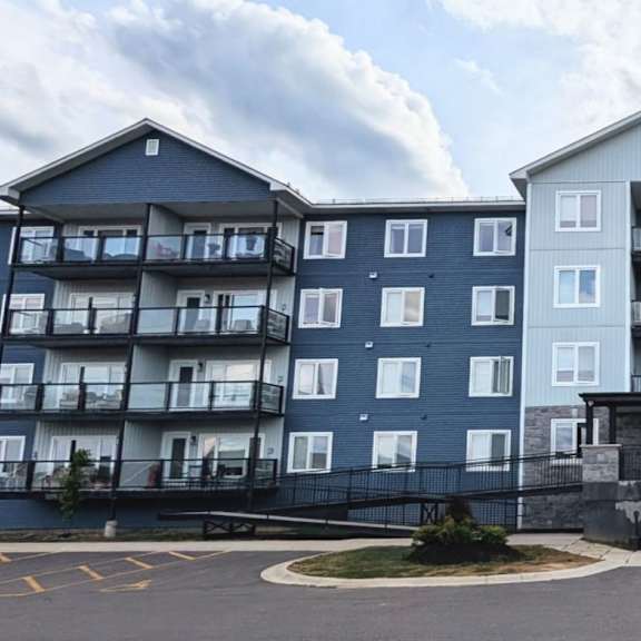 a large blue and white apartment building with a parking lot in front.