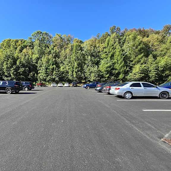 a parking lot with cars and trees in the background.