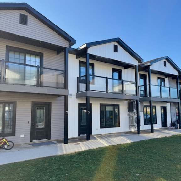 a row of modern houses with balconies and glass doors.