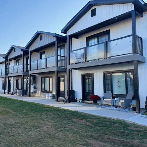 a row of modern houses with balconies and glass doors.