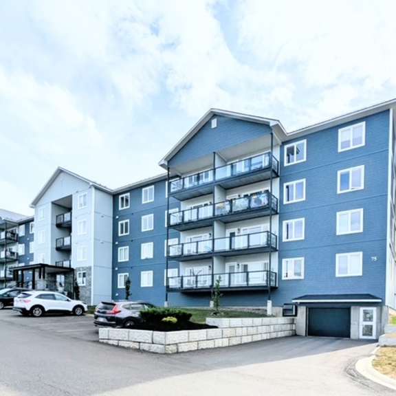 a large blue and white apartment building with cars parked in front.