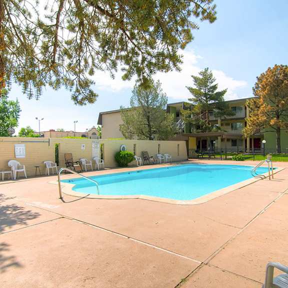 a pool surrounded by chairs and trees.