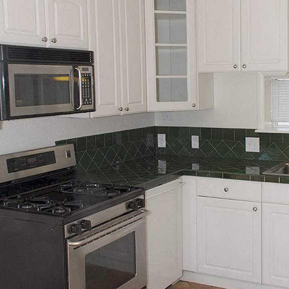 a kitchen with white cabinets and a black stove top oven.