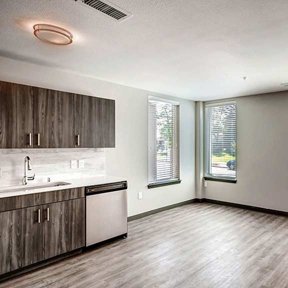 a kitchen with wooden cabinets and a window overlooking a street.