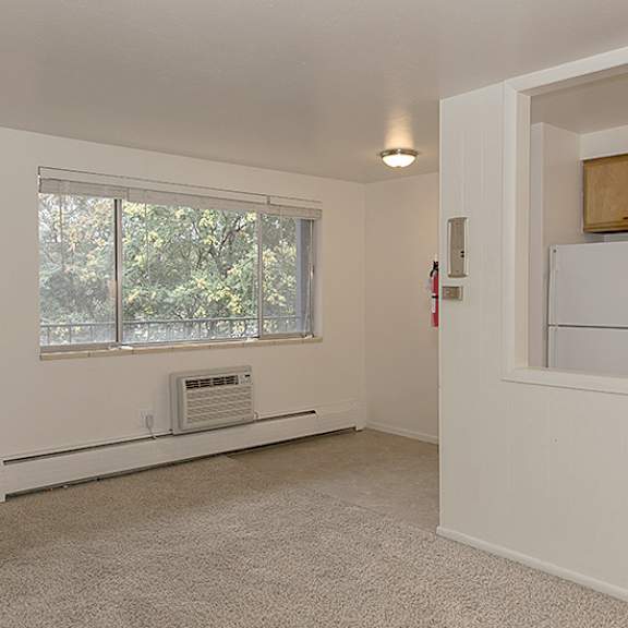 a white room with a window and a white refrigerator.