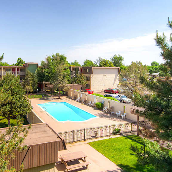 a swimming pool is surrounded by a fence and trees.
