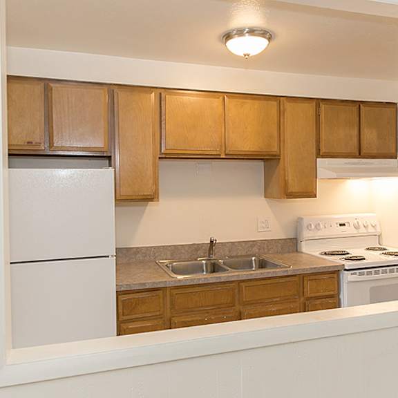 a kitchen with white appliances and wooden cabinets.