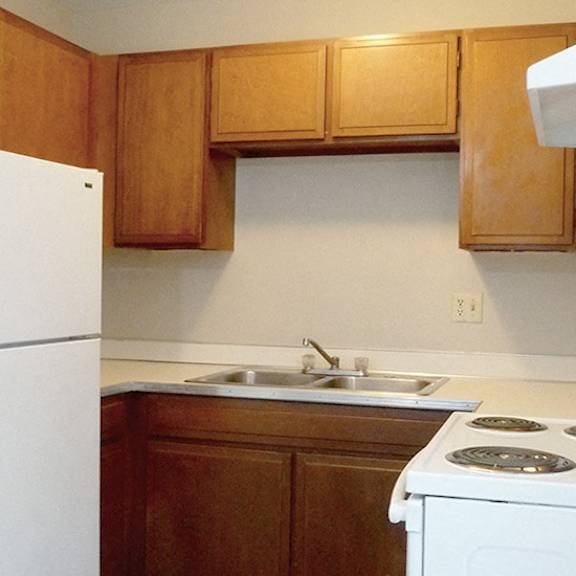 a white refrigerator is in a kitchen with wooden cabinets.