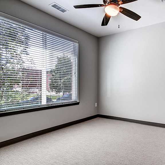 a room with a ceiling fan and a window with blinds.